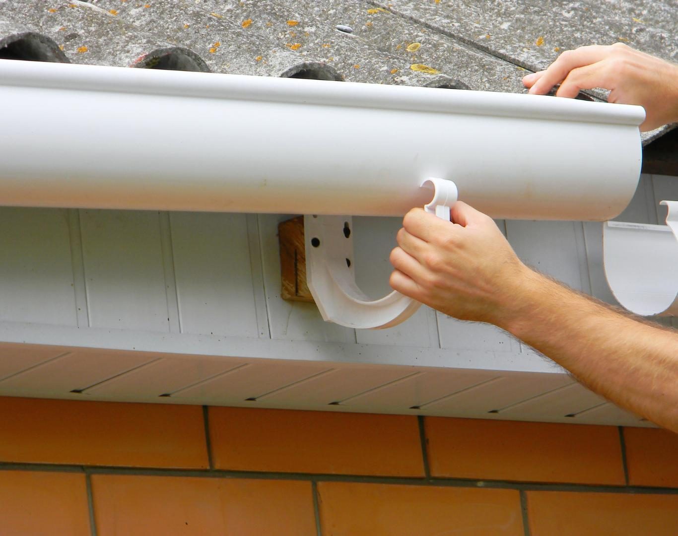Gutter installer near me in Throop, NY attaching downspouts for efficient drainage